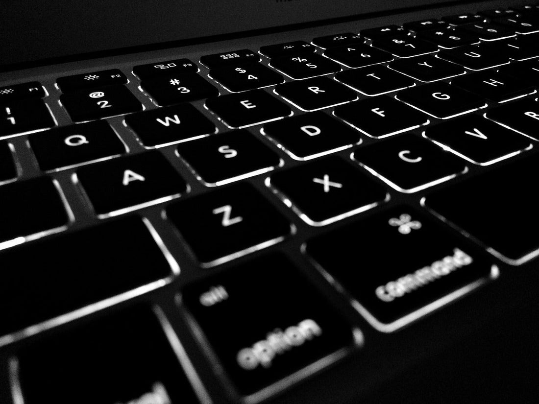 Close-up of a laptop keyboard with illuminated keys in a dark environment.