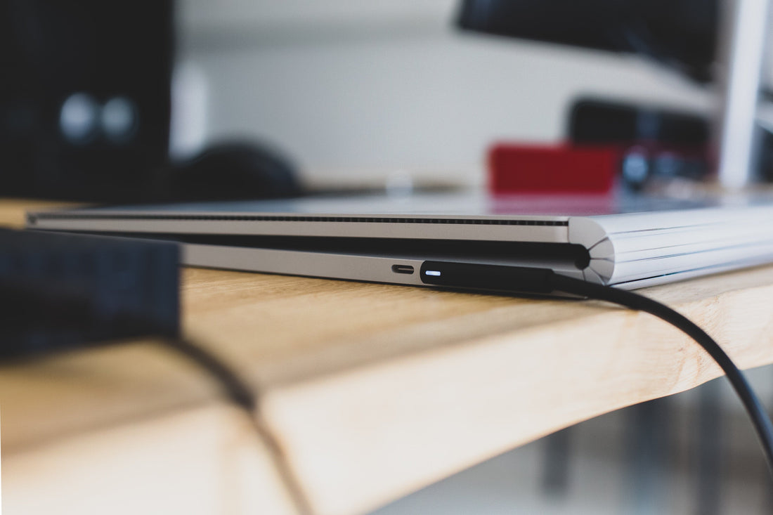 A close-up of a laptop on a desk, with a cable plugged into the USB-C port.