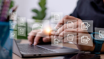 Person using a laptop with floating file and folder icons around them, indicating digital file management.
