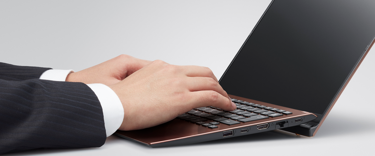 Person typing on a VAIO laptop with an ergonomic hinge design, ensuring comfort and showcasing multiple connectivity ports.