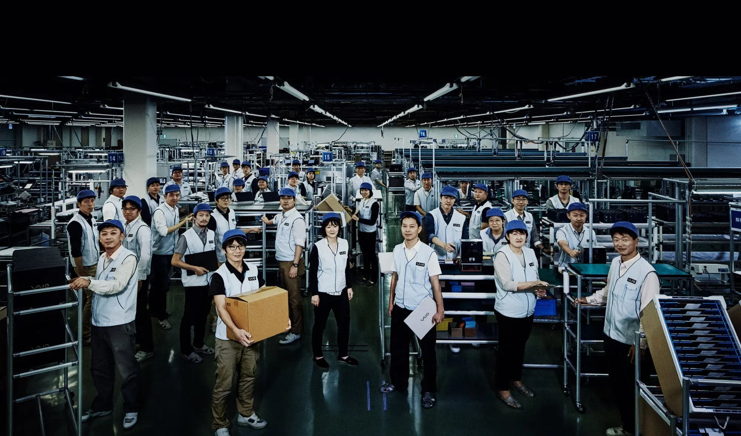 Factory workers in uniforms standing in an organized manufacturing facility, engaged in various tasks and operations.
