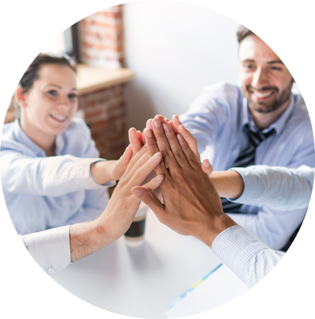 A group of professionals in business attire joining hands for a team high-five, symbolizing teamwork and collaboration.