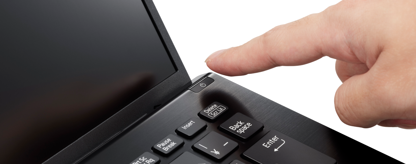Finger pressing the power button on a black laptop keyboard, highlighting its sleek design and convenient placement.