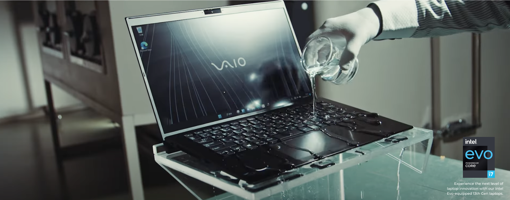 Person pours water on VAIO laptop keyboard, showcasing its water-resistant feature in a controlled test environment.