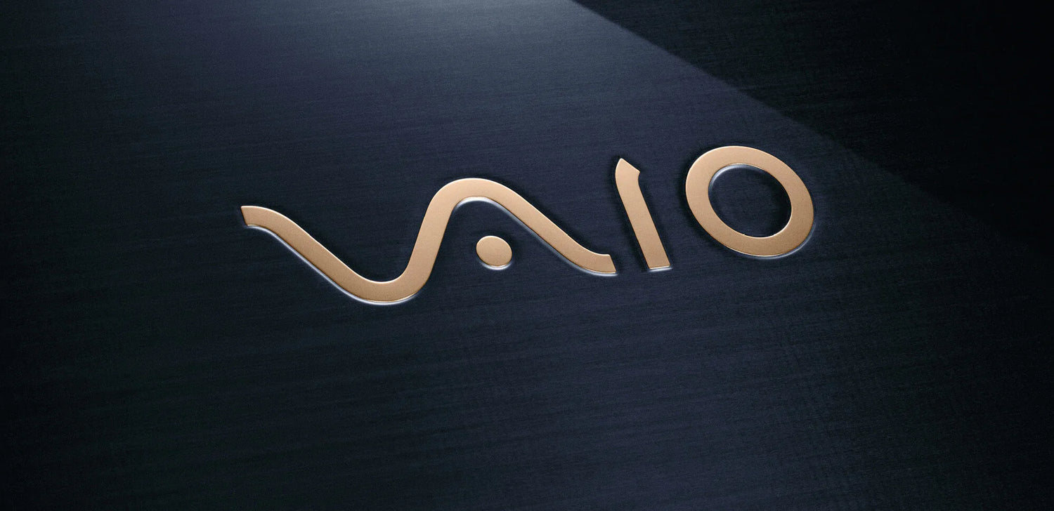 Close-up of the VAIO logo in metallic gold on a dark brushed metal laptop surface.