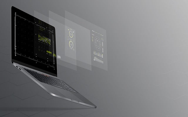 A laptop floating with digital interface screens displayed in the background, showing data and graphical elements.