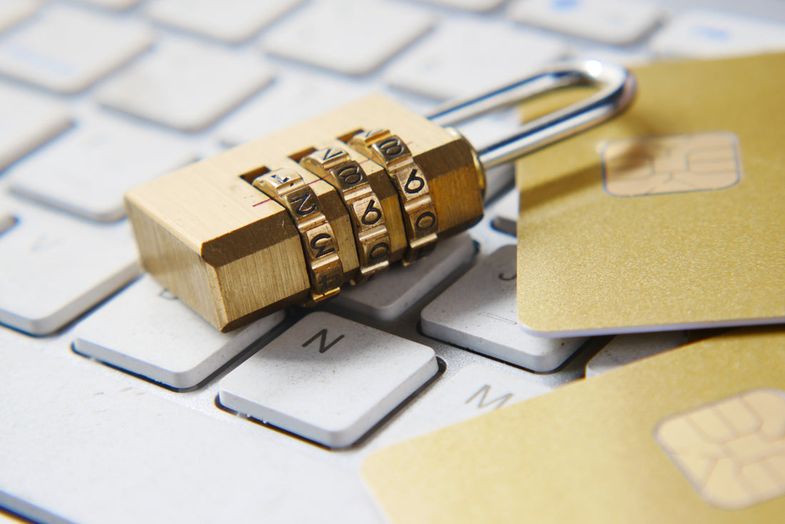 A close-up of a combination lock placed on a keyboard with two credit cards next to it, symbolizing security.