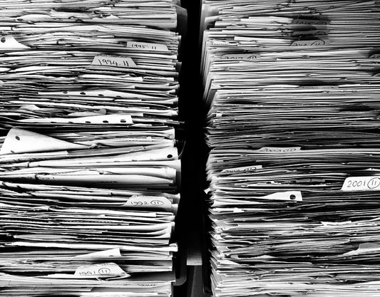 Stacks of paper files organized by year, with labels visible on the edges of the folders.